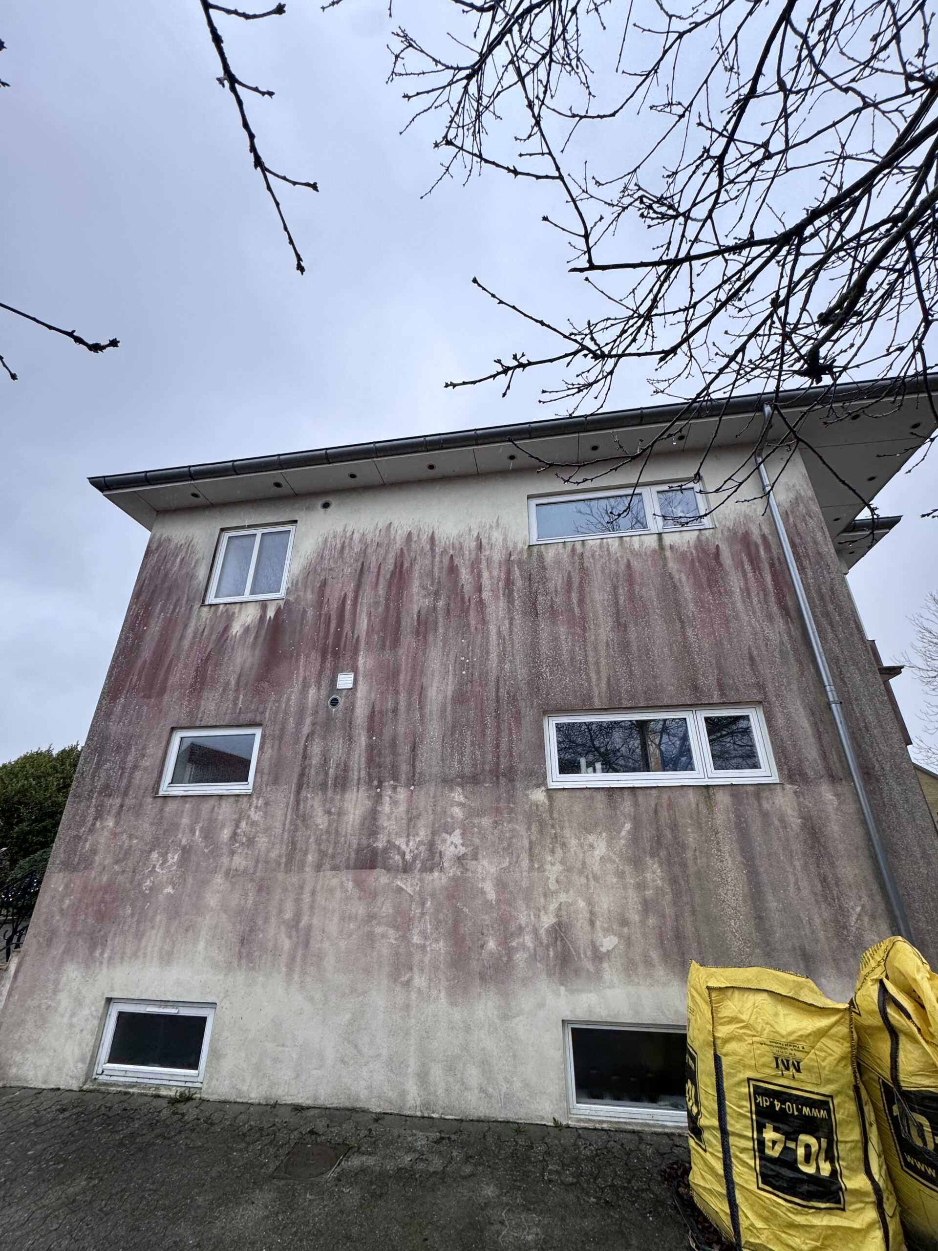 Pudset facade i Horsens med kraftige røde alger før facaderens – 2026