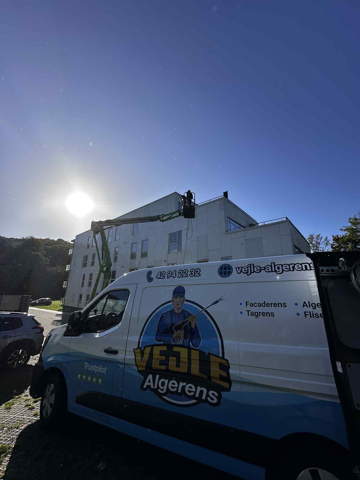 Algebehandling af en stor bygning i Vejle med lift og Vejle Algerens servicebil i forgrunden